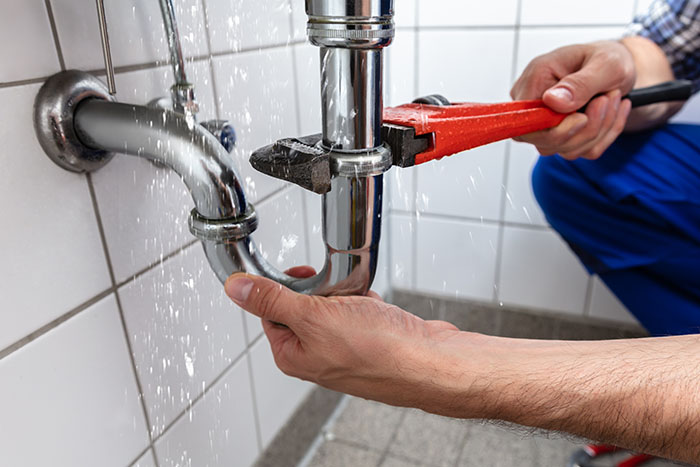 man fixing a pipe under a sink